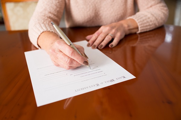 Senior Woman Signing Last Will And Testament At Home